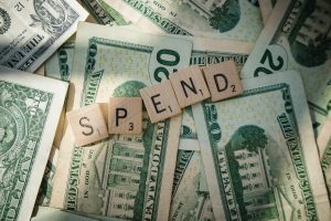 Scrabble letters spelling 'spend' on American bills, sinifying the consumer financial trends.