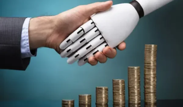 A image of a human shaking hand with a robot with coins in the background, as a way to signal artificial intelligence is transforming modern consumer lending.