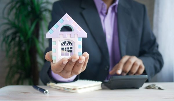 A man holding a house miniature in his hand, signifying the mortgage lending market.